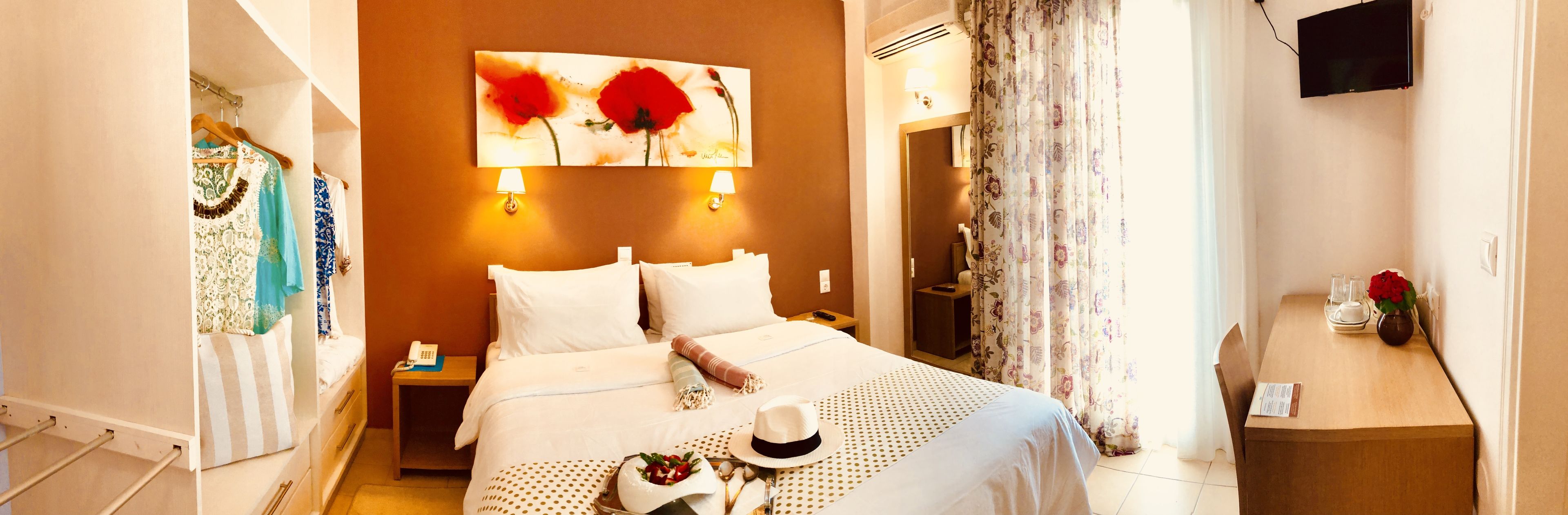 Une chambre d’hôtel avec un lit, une table de chevet, une lampe et un tableau représentant des fleurs rouges accroché au mur.