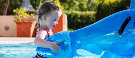Niño en una piscina con un delfín inflable azul.