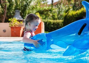 A child in a pool with a blue inflatable dolphin.