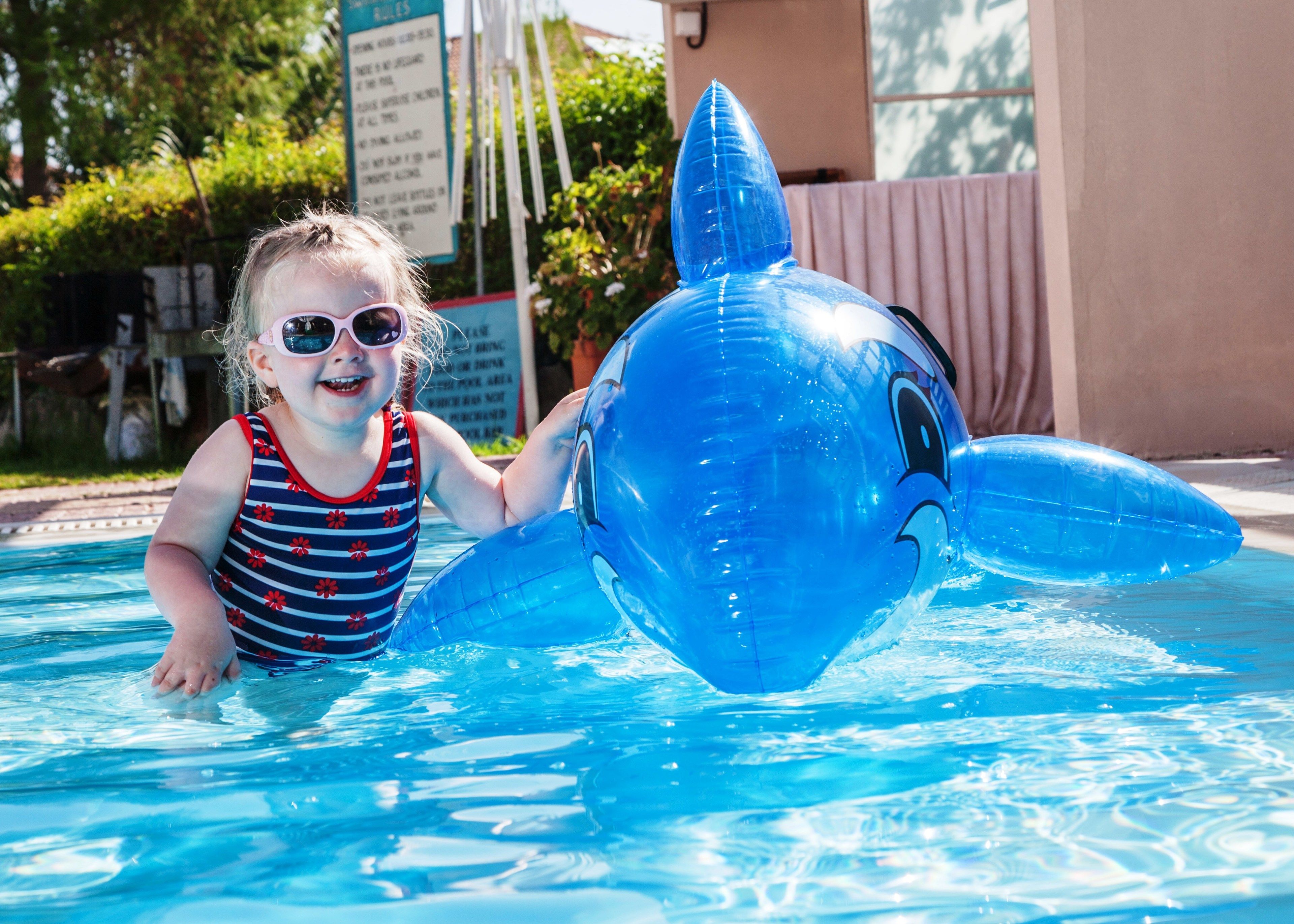 A child in a pool with a large inflatable dolphin.