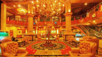 A grand lobby with a chandelier, multiple seating areas, and a staircase.