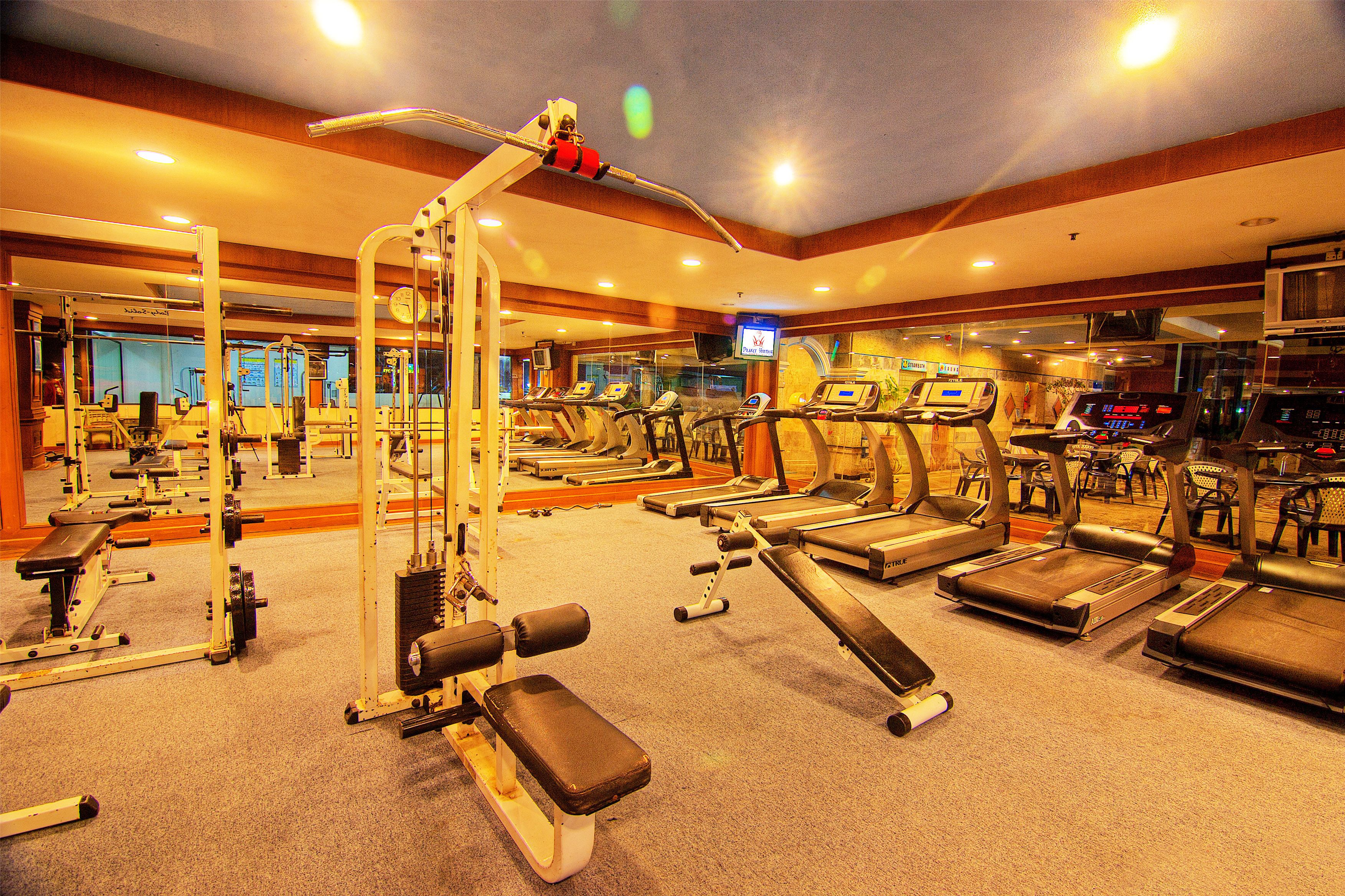 A gym with various exercise equipment, including treadmills, weight machines, and benches.