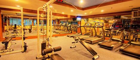 A gym with various exercise equipment, including treadmills, weight machines, and benches.