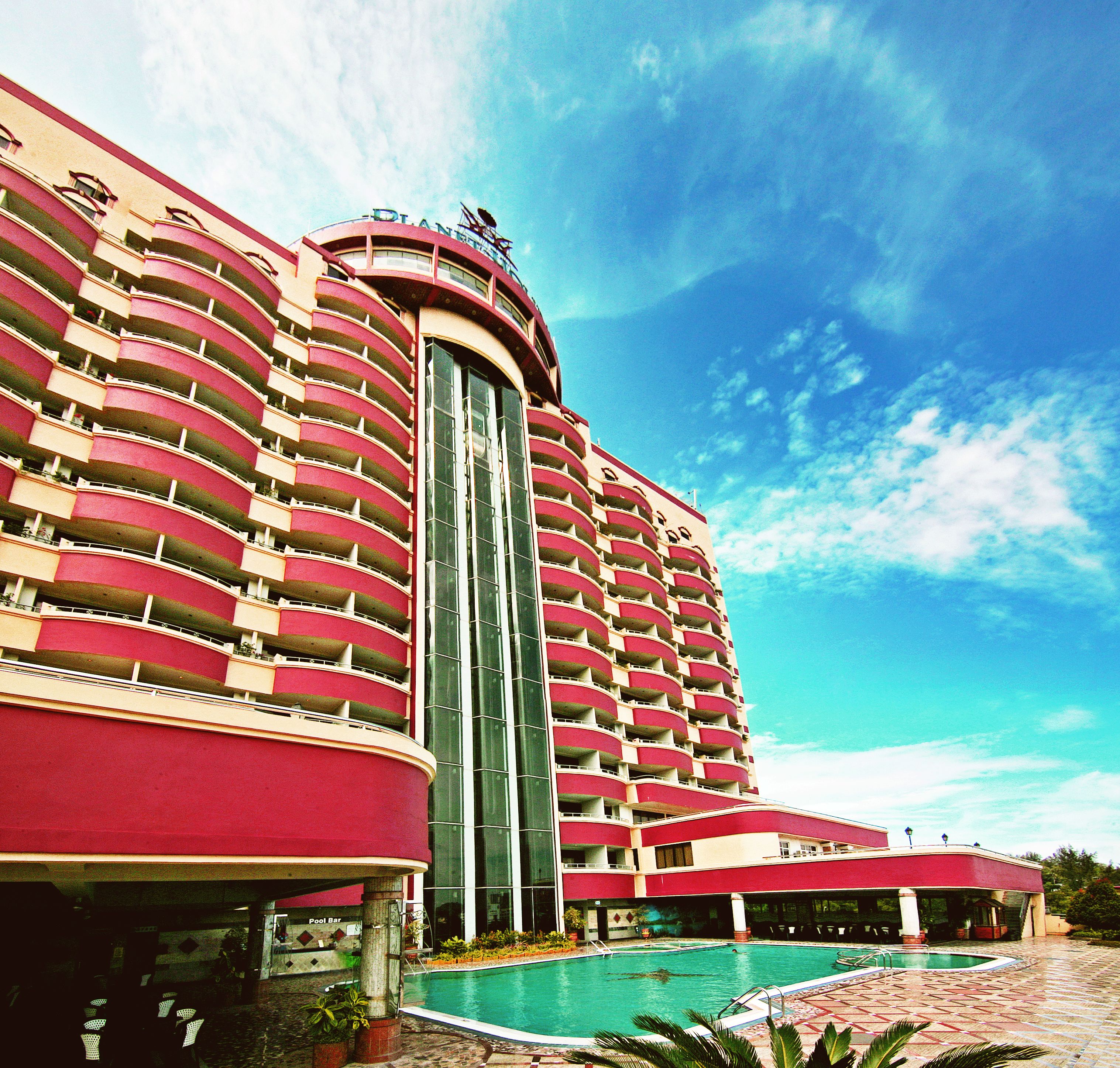 A large hotel with multiple balconies and a swimming pool.