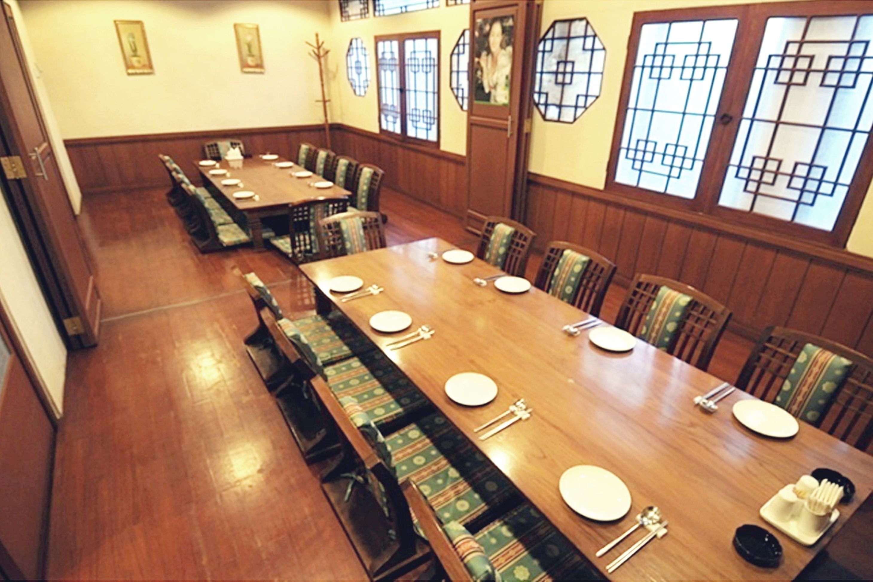 A long dining table with multiple chairs, set with plates, cutlery, and a bowl.