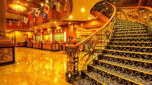 Un lobby de hotel señorial con una escalera espiral, pisos de mármol pulido y un candelabro.