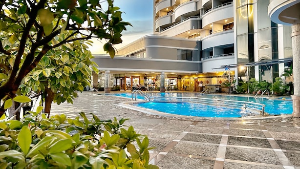Un hotel con piscina, varios balcones y un diseño arquitectónico moderno.