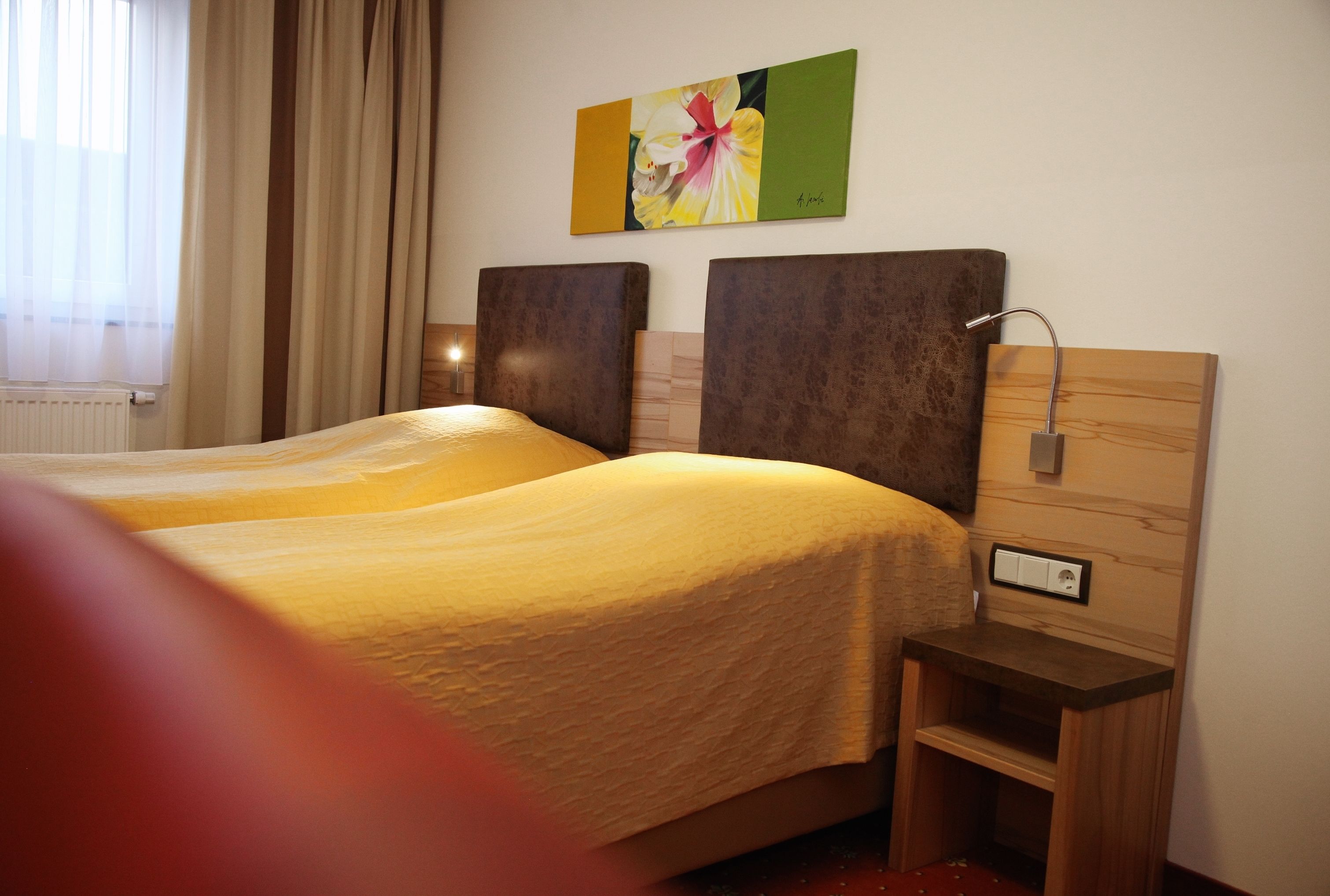 Ein Hotelzimmer mit zwei Betten, einem Nachttisch mit Lampe und einem Bild an der Wand.
