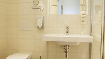 Un baño con inodoro, lavabo, espejo y ducha.