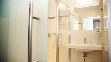 A modern bathroom with a glass shower enclosure, a white sink, and a mirror above the sink.