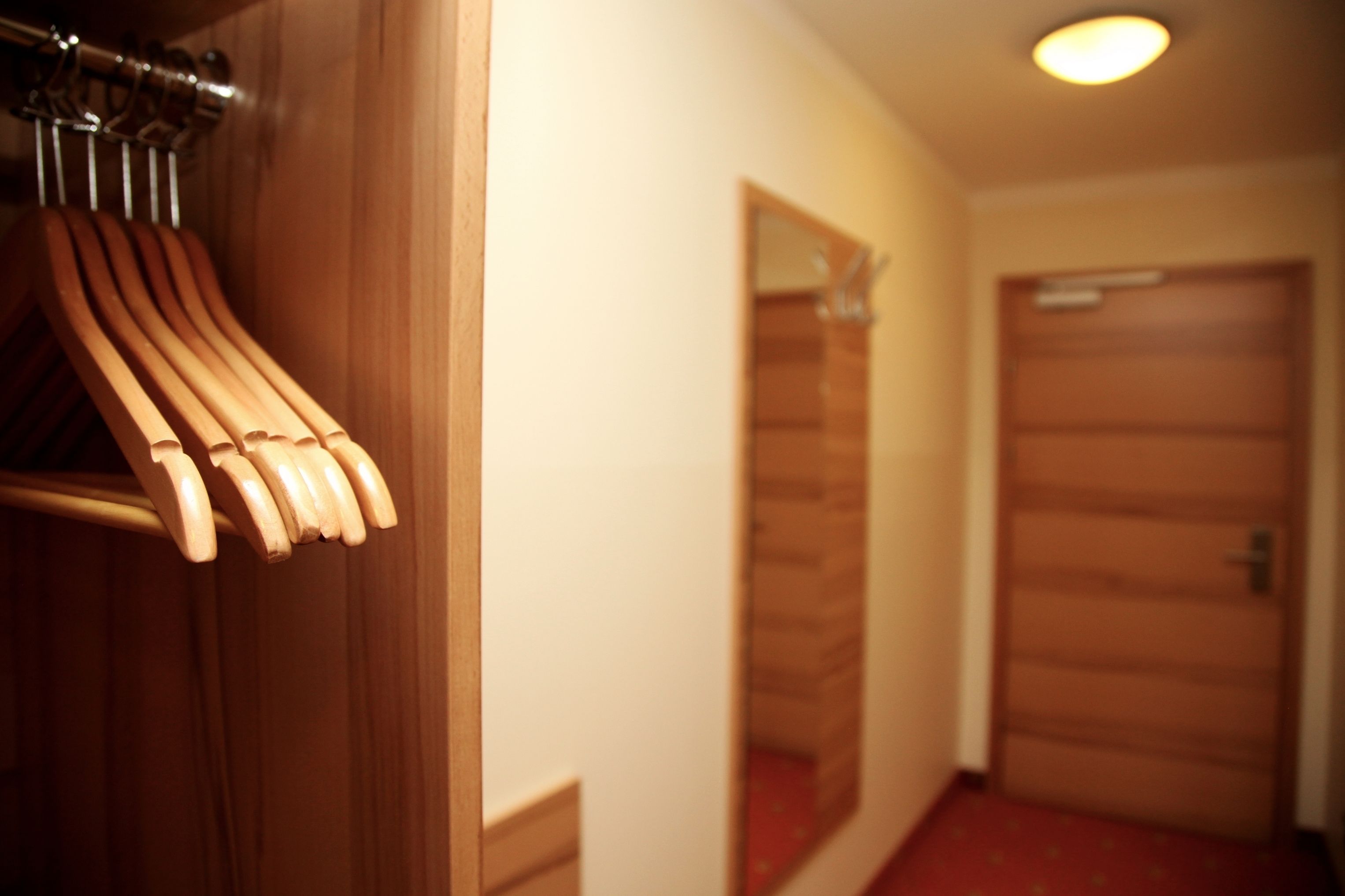 A hallway with wooden doors and a coat rack with wooden hangers.