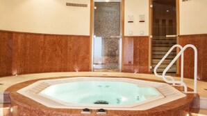 A spa area with a hot tub, marble walls, a glass door entrance, and a ceiling with recessed lighting. - Tinschert Hotel-Restaurant-Partyservice (Schwertberg)