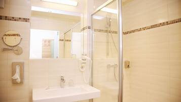 A bathroom with a sink, mirror, and glass-enclosed shower.