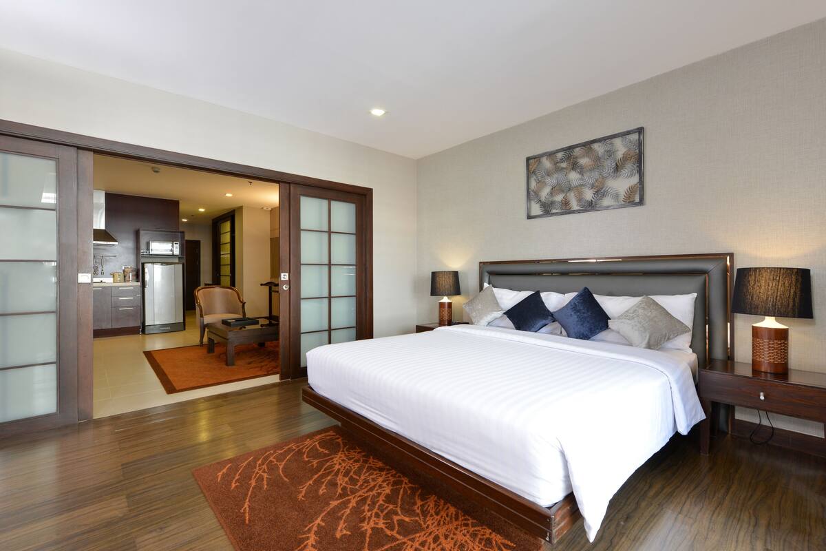 Een hotelkamer met een groot bed, een bureau, een stoel en uitzicht op de keuken.