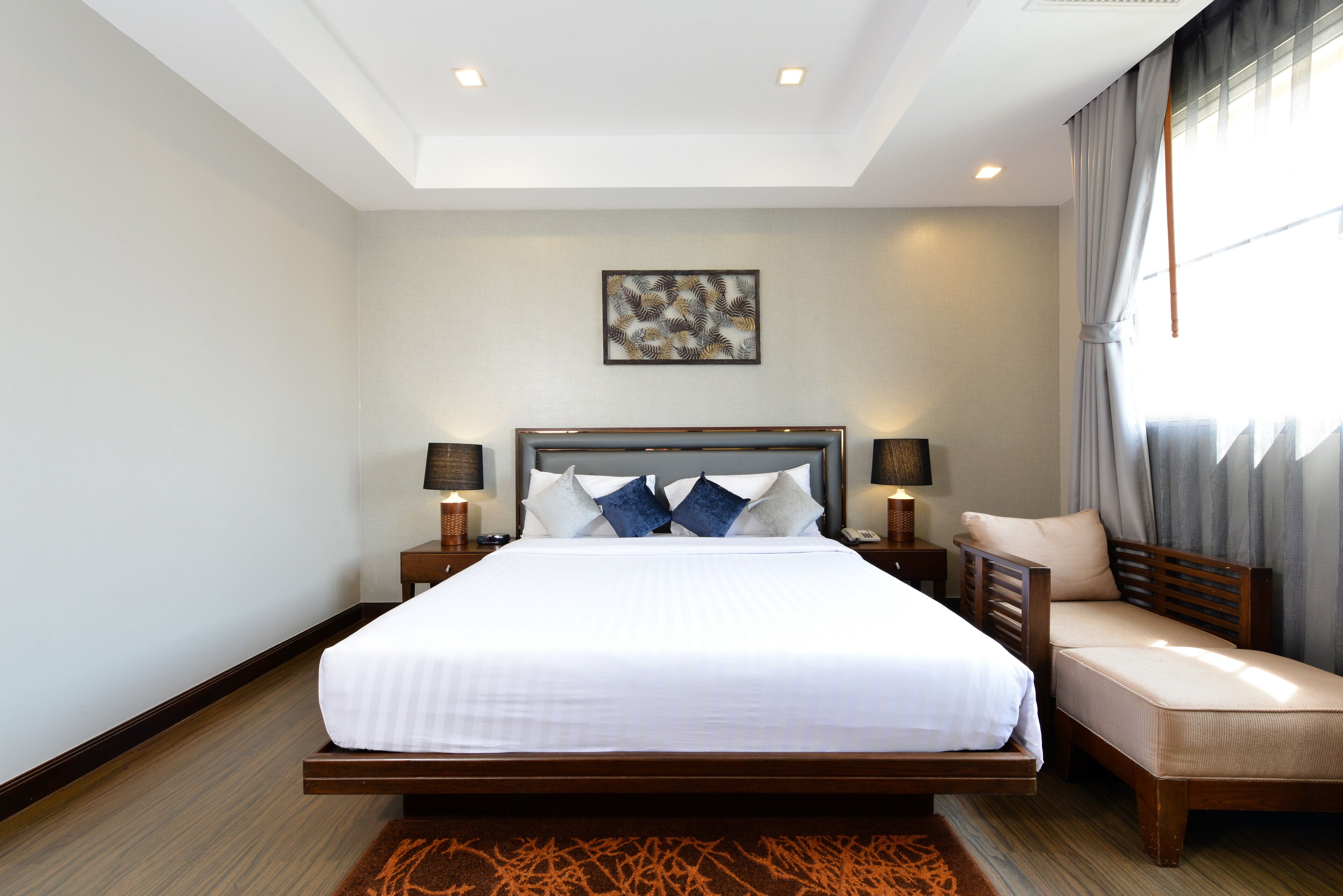 Une chambre spacieuse avec un grand lit, des tables de chevet, une petite table, une chaise et un luminaire au plafond.