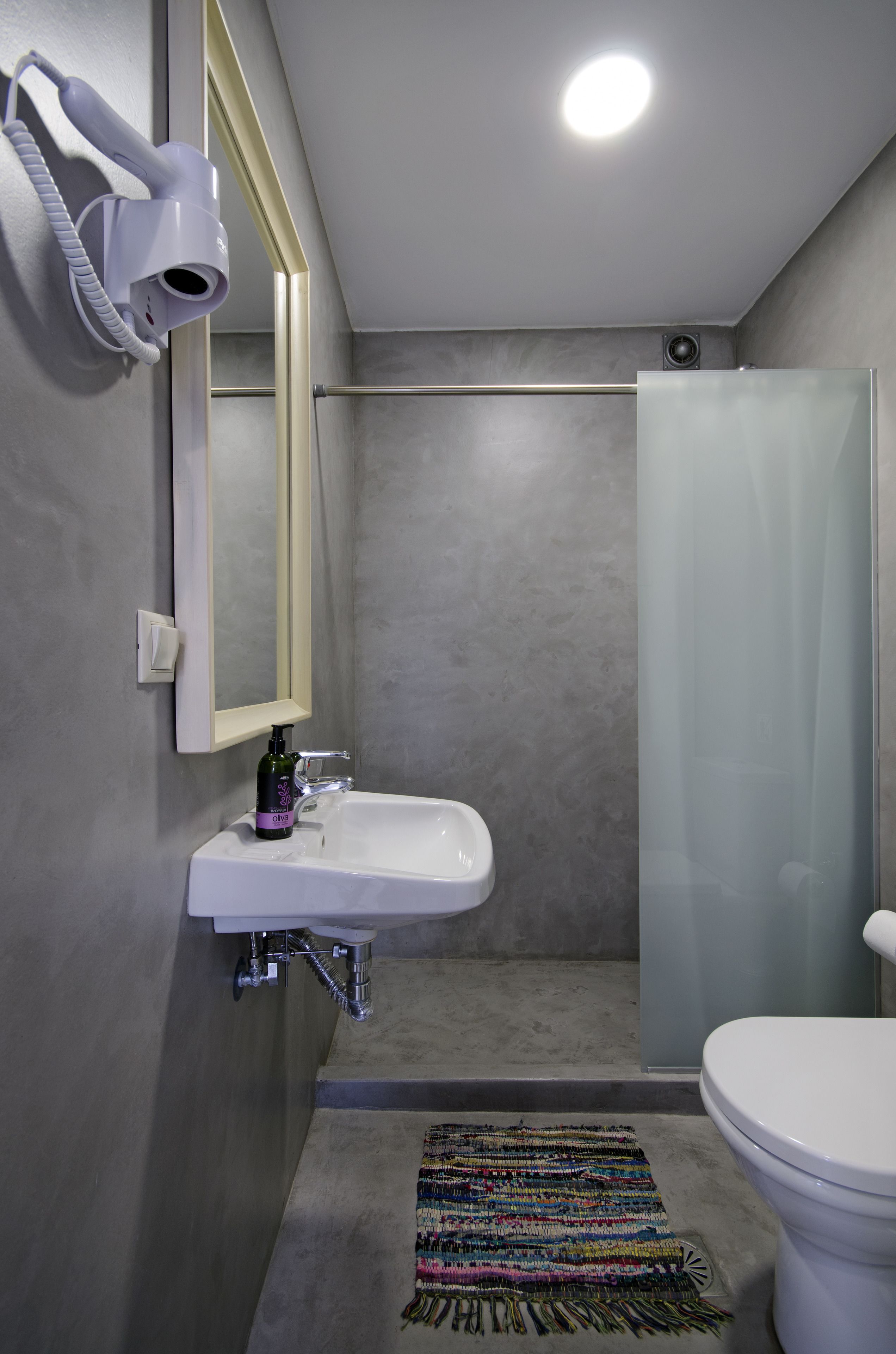 Une salle de bain avec un lavabo blanc, un miroir, un sèche-cheveux, une douche et des toilettes.