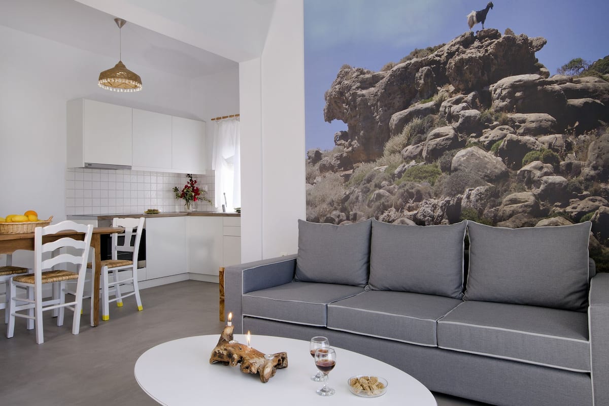 Una sala de estar moderna con una mesa de centro blanca, un sofá gris y una zona de comedor con una mesa y sillas blancas.