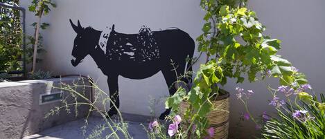 Silueta negra de un burro montada en la pared, rodeada de follaje y flores.