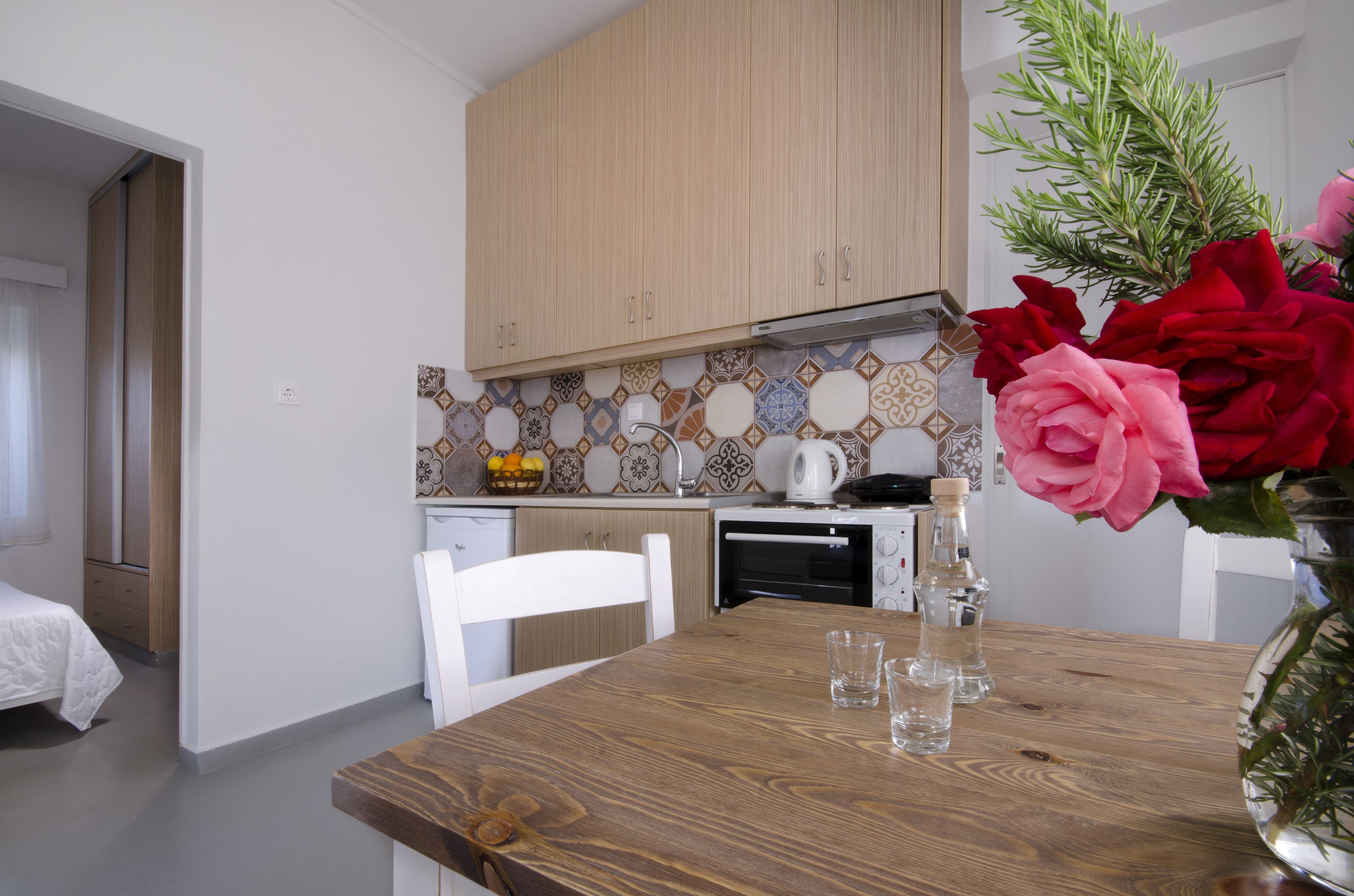 A compact kitchen with wooden cabinets, a tiled backsplash, and a dining area with a wooden table.