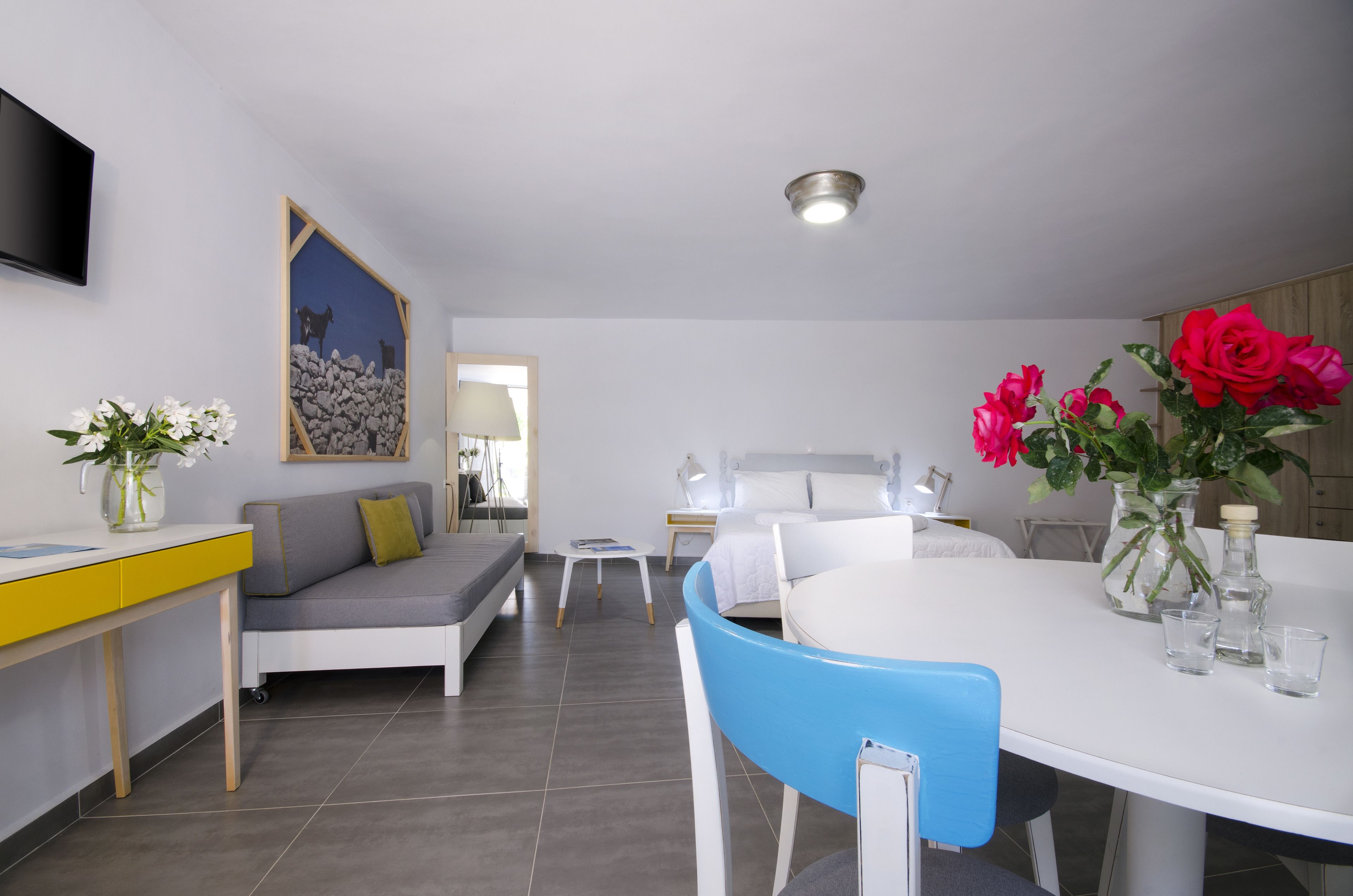 Una sala de estar moderna con un sofá, una mesa de comedor y un televisor montado en la pared.