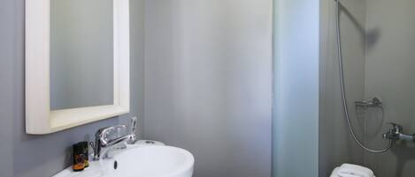 A bathroom with a white sink, toilet, and shower.