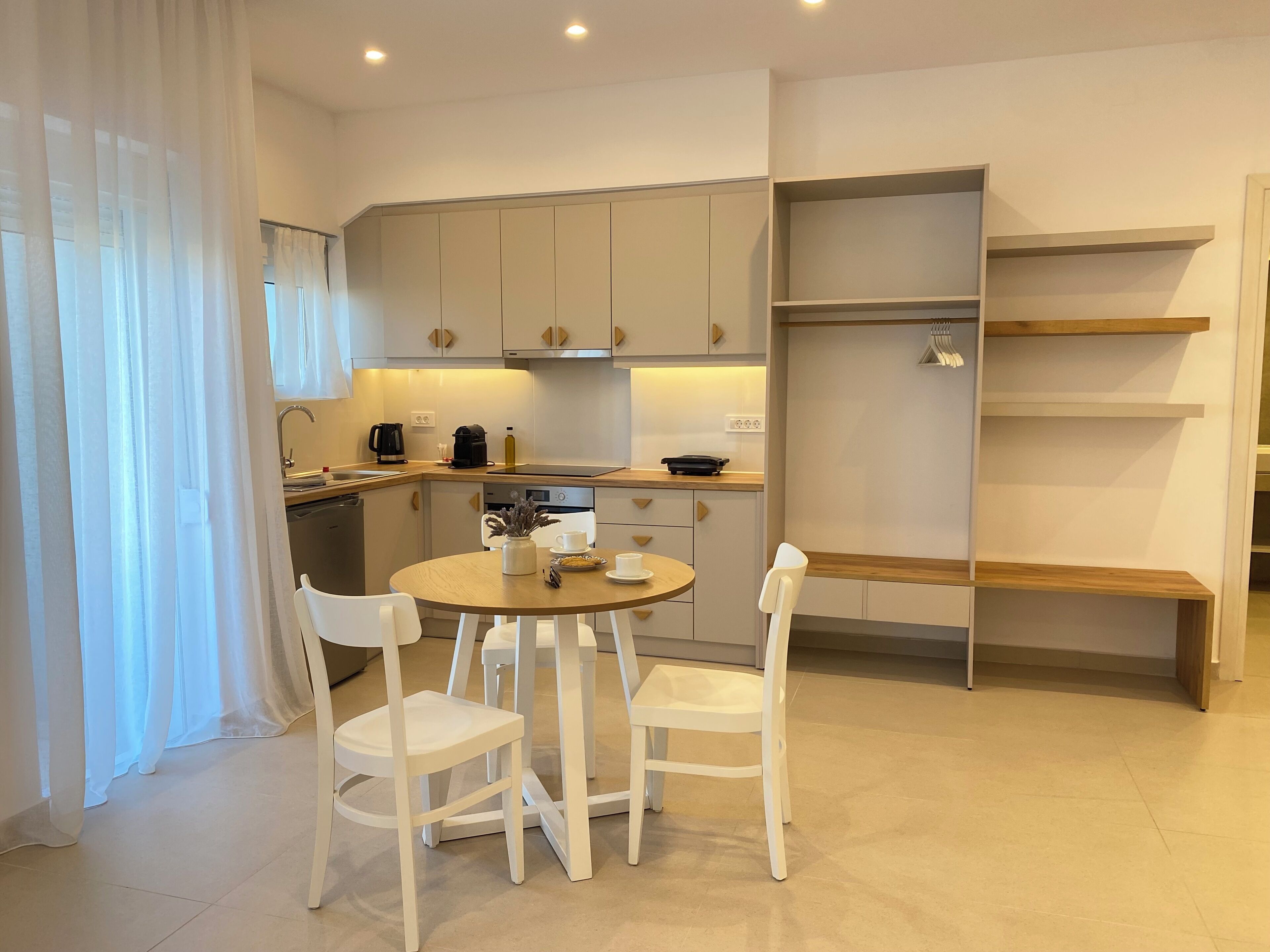 Una cocina moderna con armarios blancos, una mesa de comedor redonda y sillas blancas.