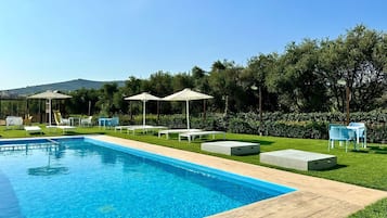 Een seizoensgebonden buitenzwembad, ligstoelen bij het zwembad