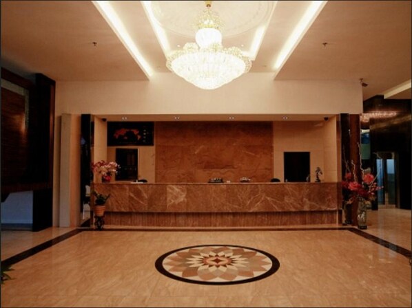A hotel reception area with a marble counter, a large chandelier, and a decorative floor pattern. - Hotel S. Damansara (Batu Caves)