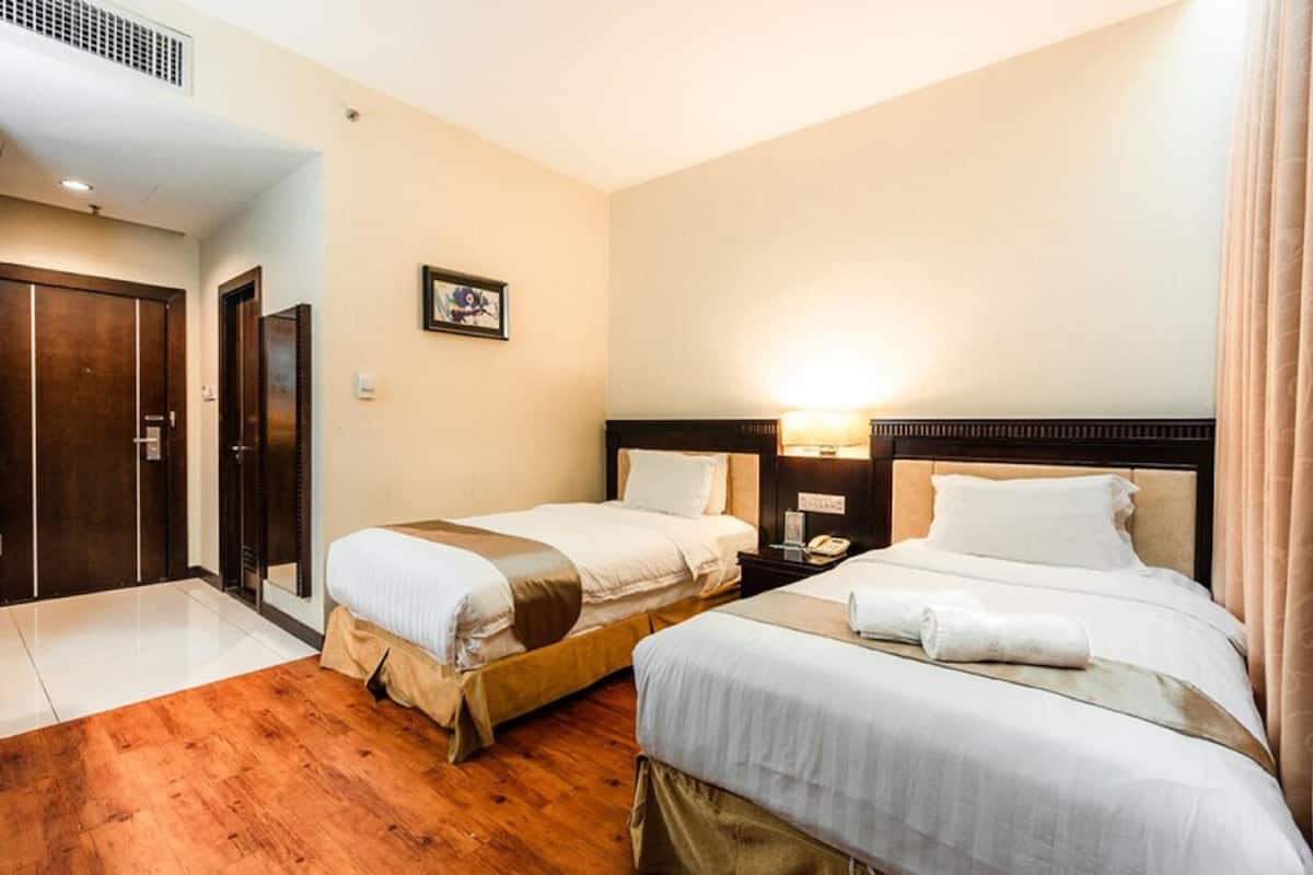 Ein Hotelzimmer mit zwei Betten, Holzboden, einem Wandbild und einem Nachttisch mit einer Lampe.