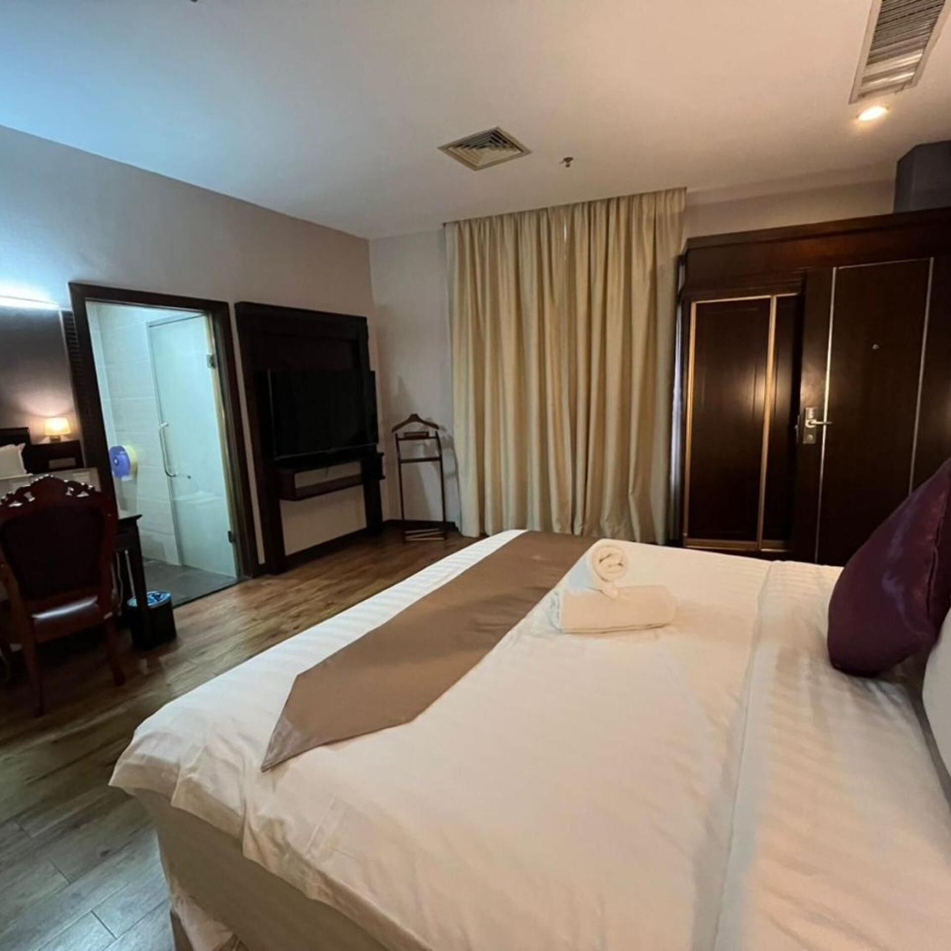 Ein Hotelzimmer mit Bett, Fernseher, Kleiderschrank und Badezimmer.