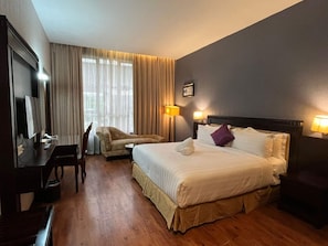 A hotel room with a bed, a desk, a chair, a TV, and a window with curtains. - Hotel S. Damansara (Batu Caves)