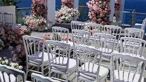 Un espace extérieur aménagé avec des tables et des chaises blanches, situé en bord de mer et agrémenté de compositions florales.