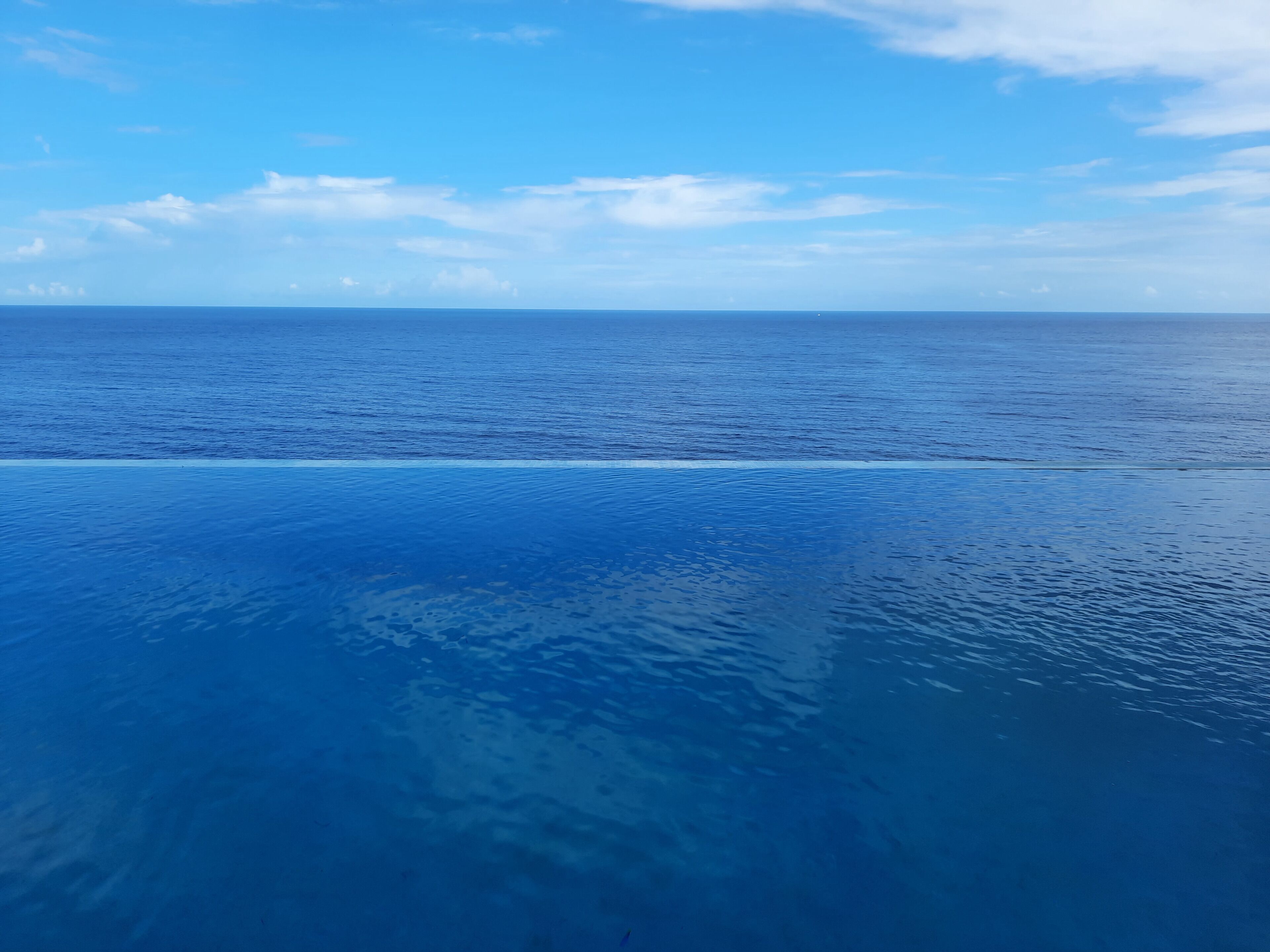 A view of the ocean from a high vantage point, with a clear sky and calm water.