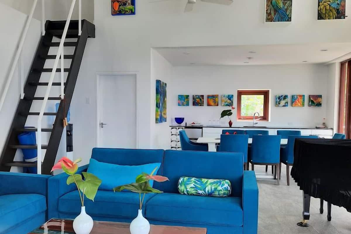 Een moderne woonkamer met een blauwe bank, een salontafel en een trap.