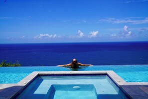 Una persona relajándose en una piscina con vista al océano.