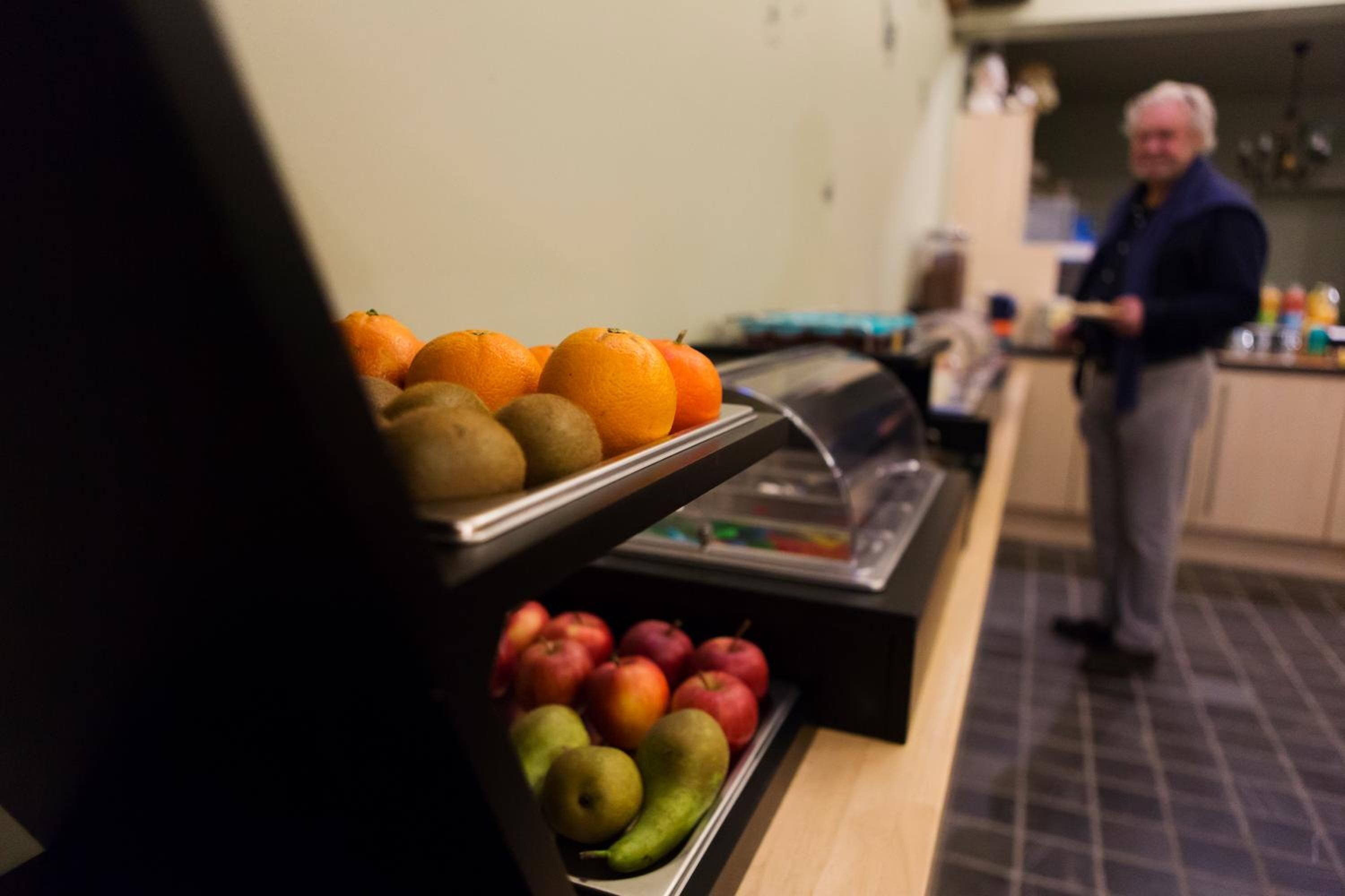 A buffet counter with fruits and a person standing in the background.