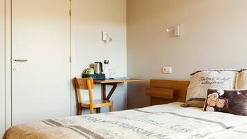 A bedroom with a bed, a desk, and a chair. There are pillows with text and a picture on the bed.