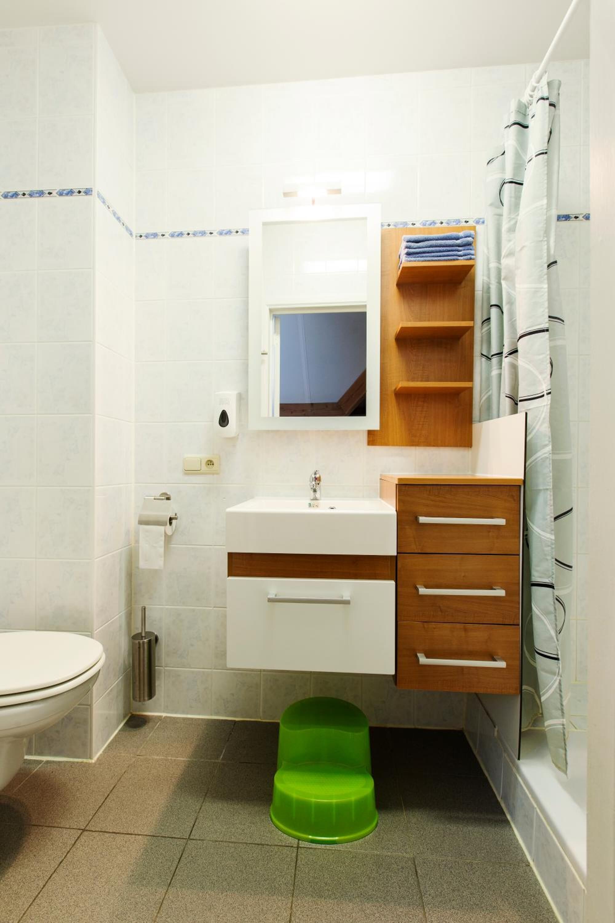 Ein Badezimmer mit Toilette, Waschbecken, Holzschrank und Podest.