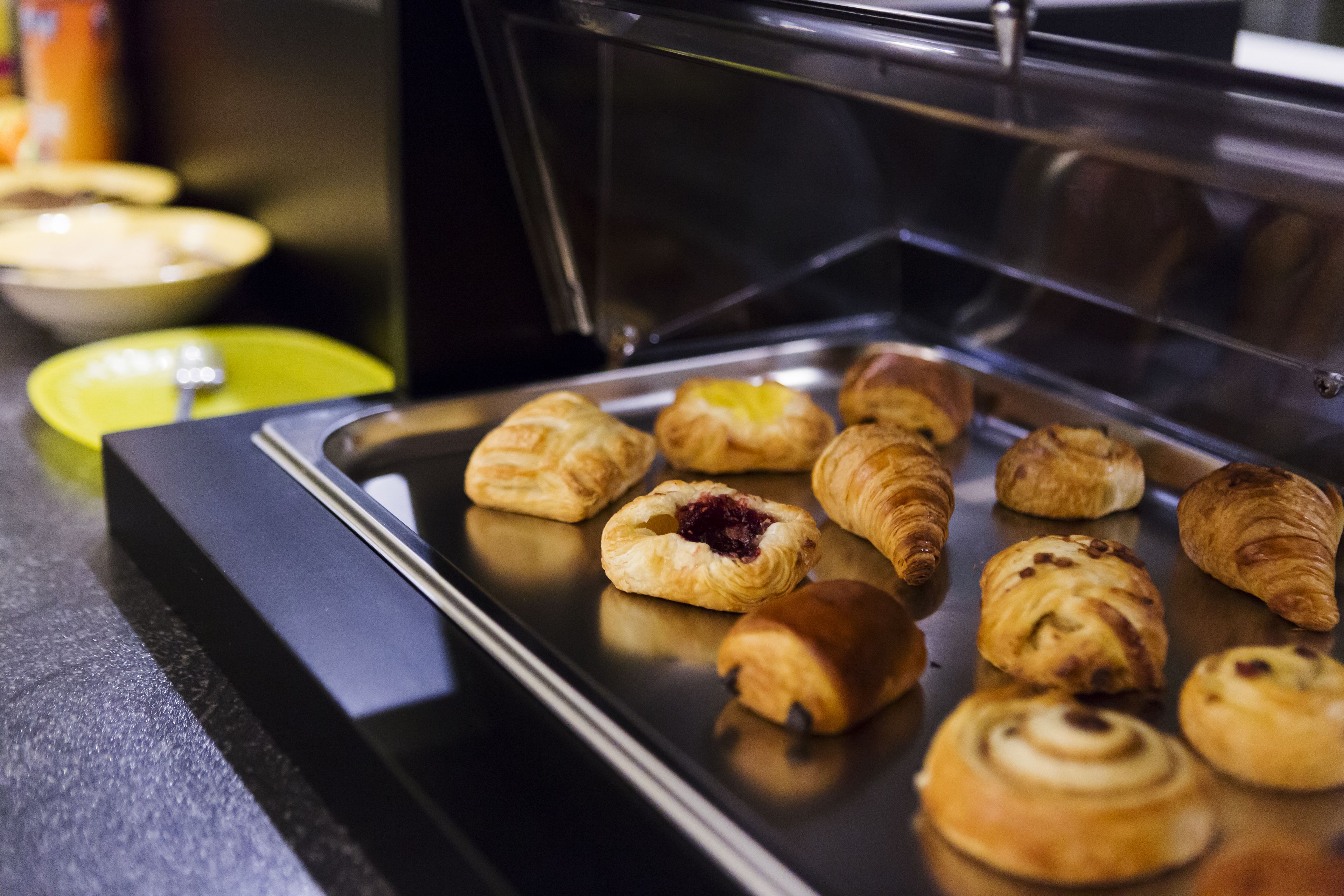 A display case with various pastries, including croissants and muffins, on a tray.