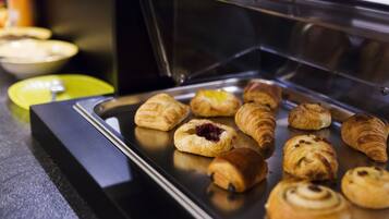 A display case with various pastries, including croissants and muffins, on a tray.