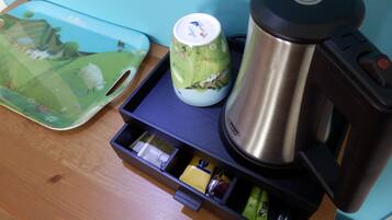 A kitchen counter with a coffee maker, a mug, and a tray with a teapot and tea bags.