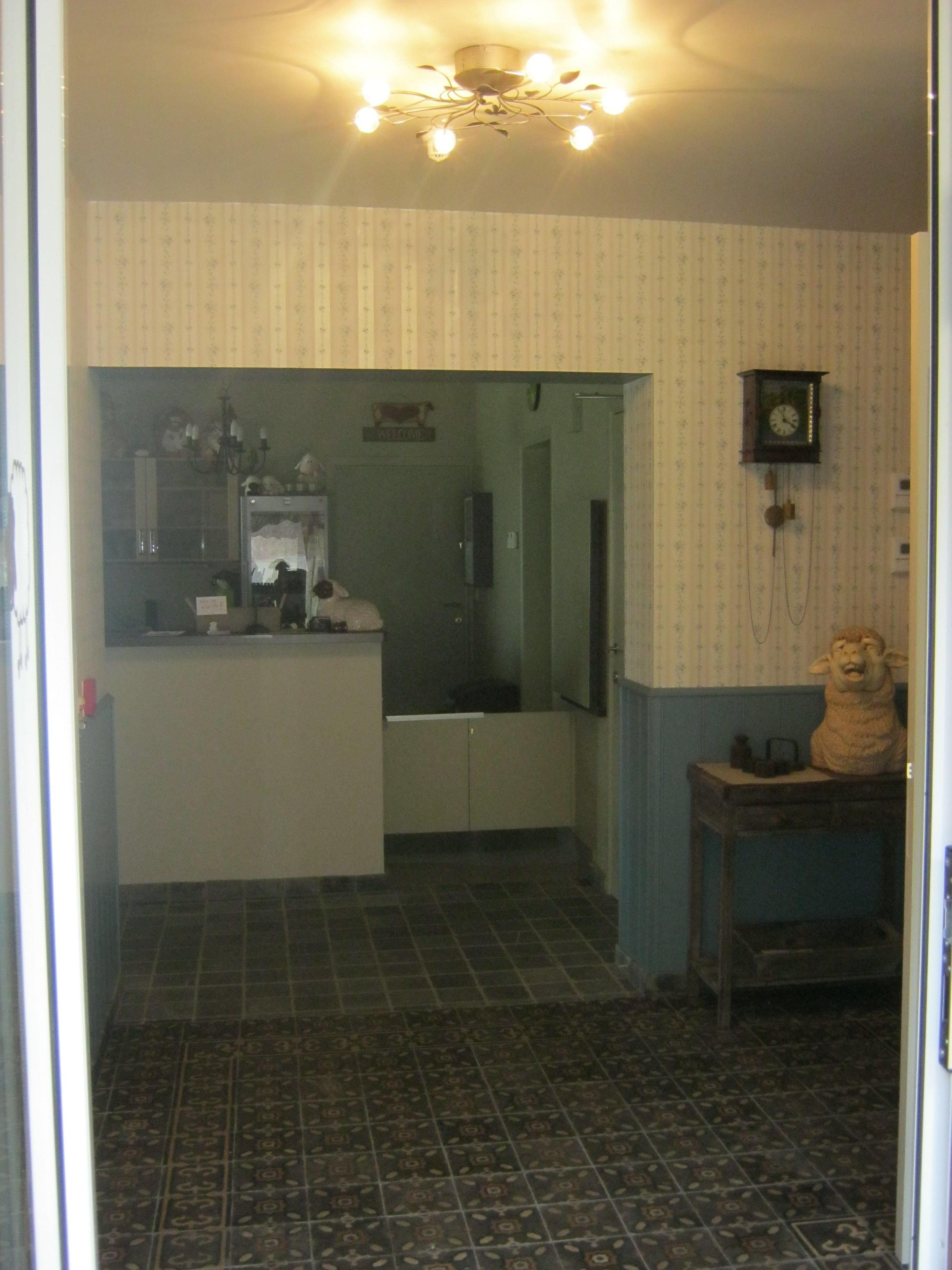 Una cocina con piso de baldosas, un refrigerador, un lavamanos y un reloj en la pared.