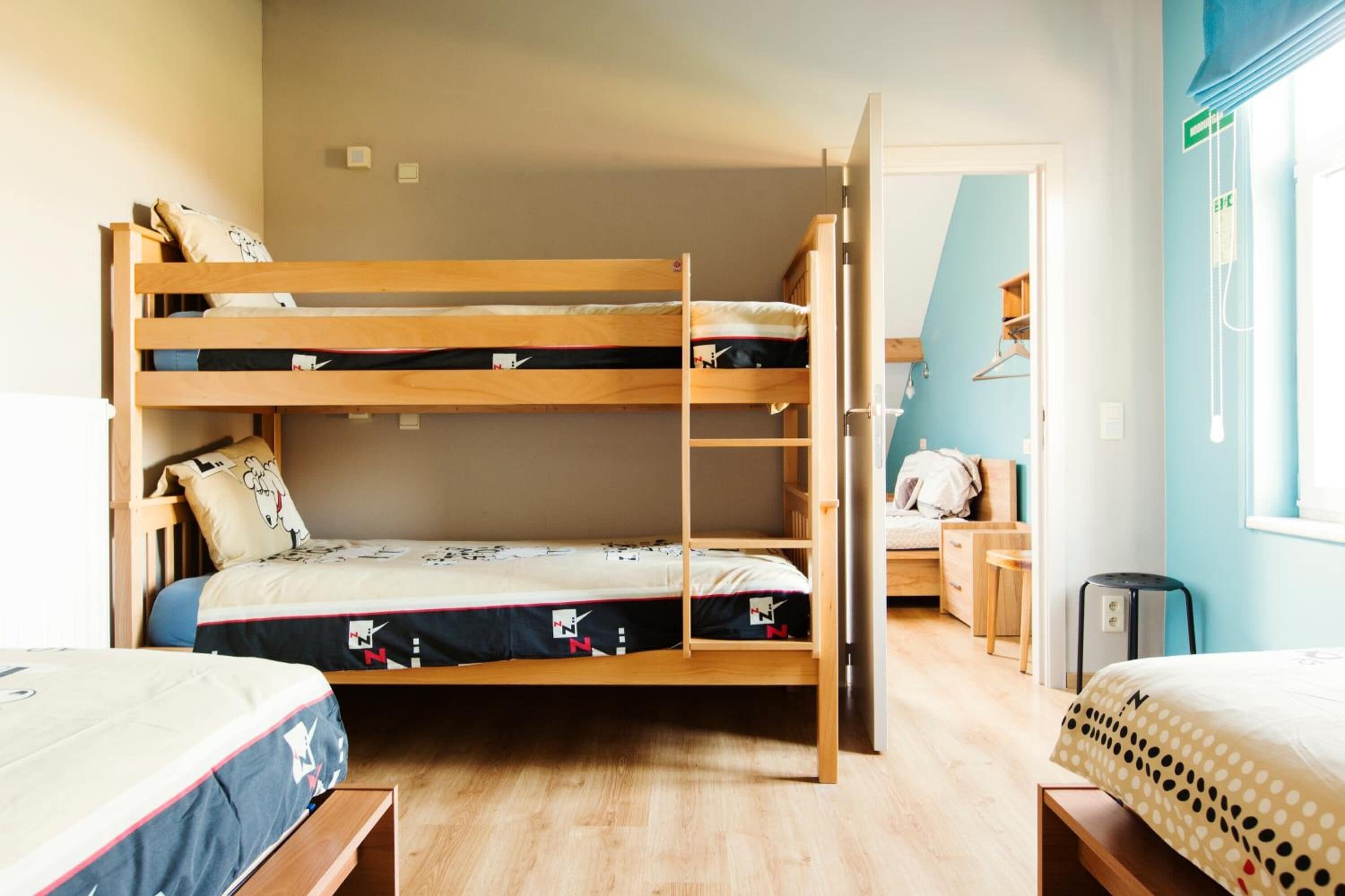 A bunk bed room with a ladder, a desk, and a chair.