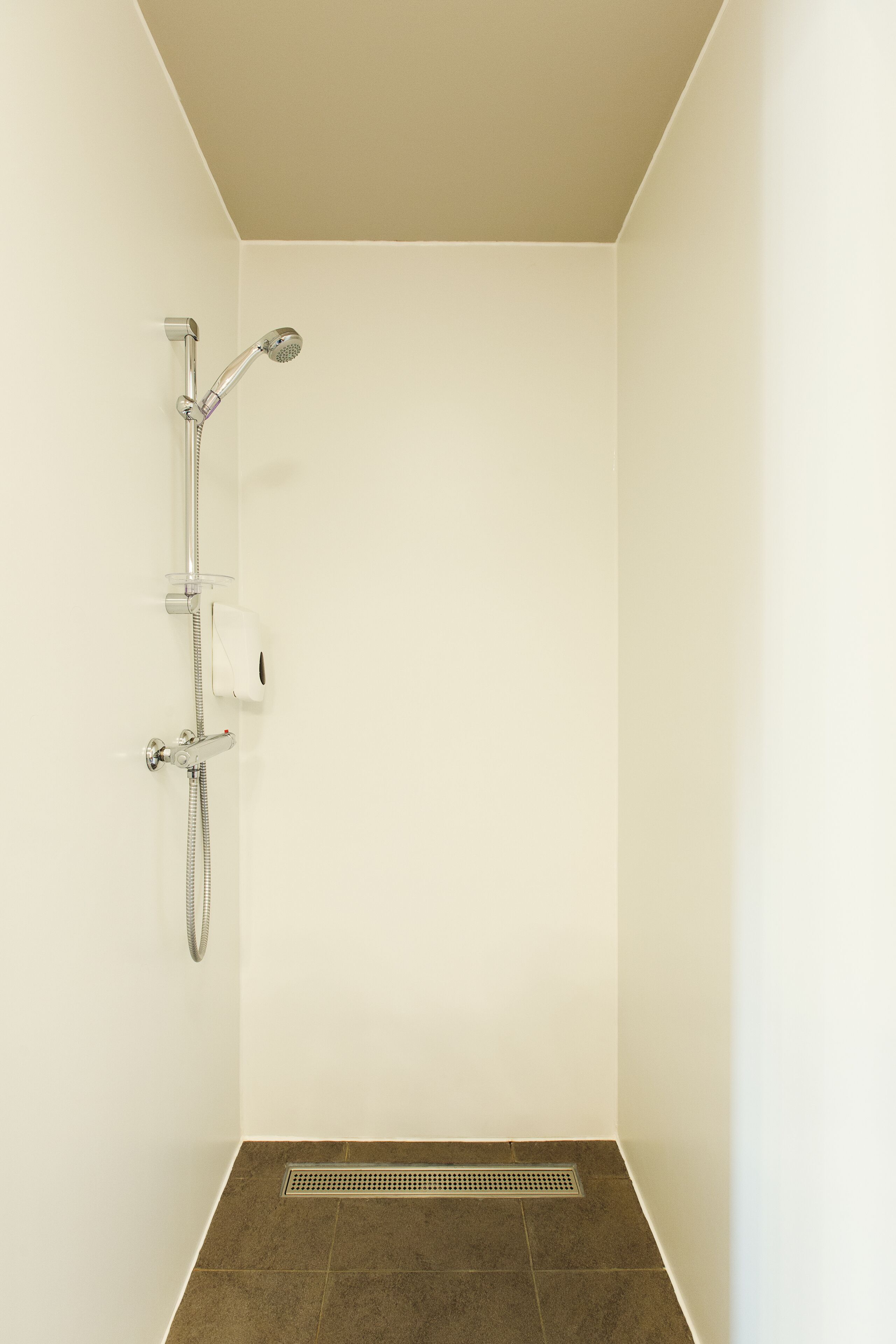 A shower with a handheld showerhead and a wall-mounted faucet.