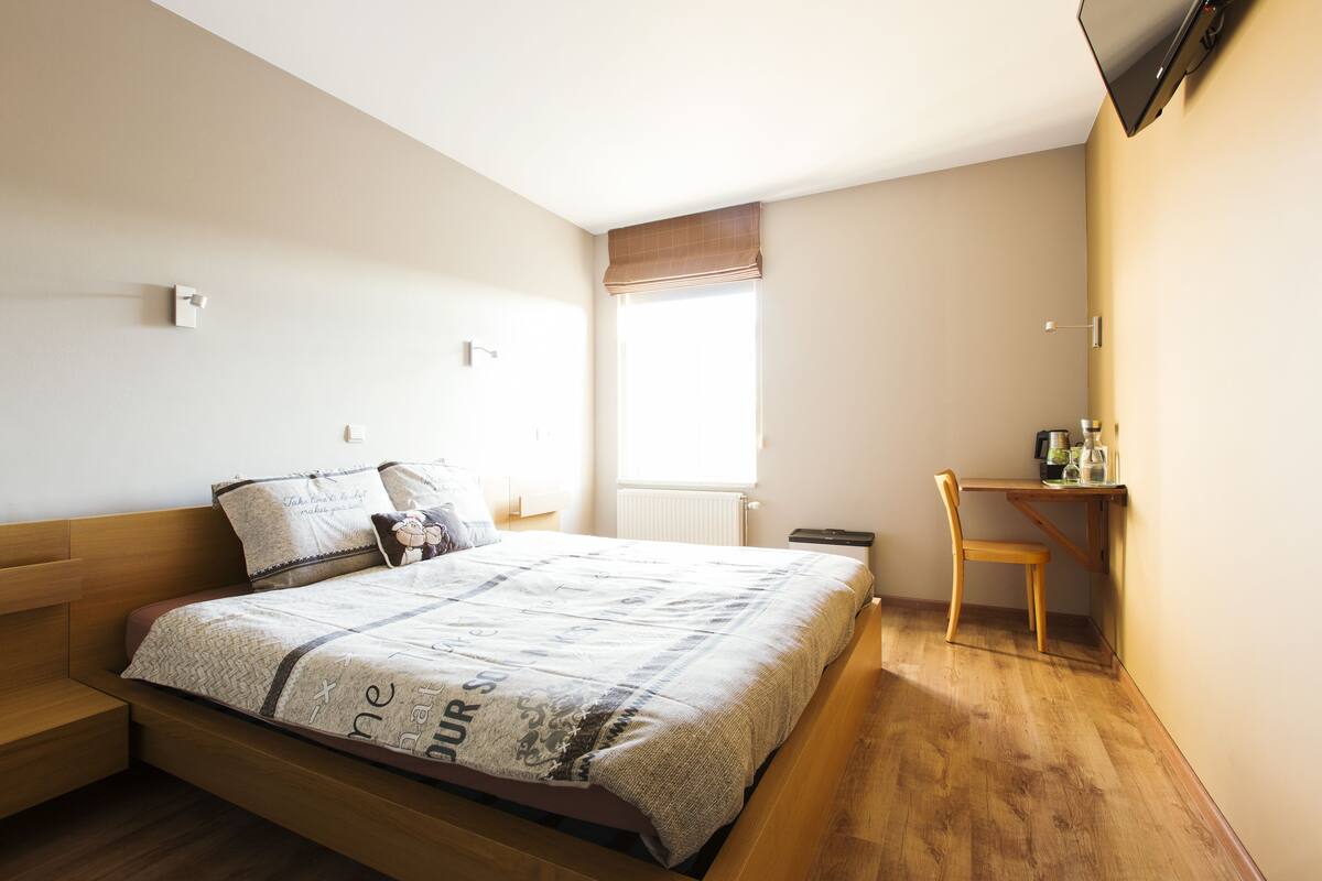 A bedroom with a bed, a desk, and a chair.