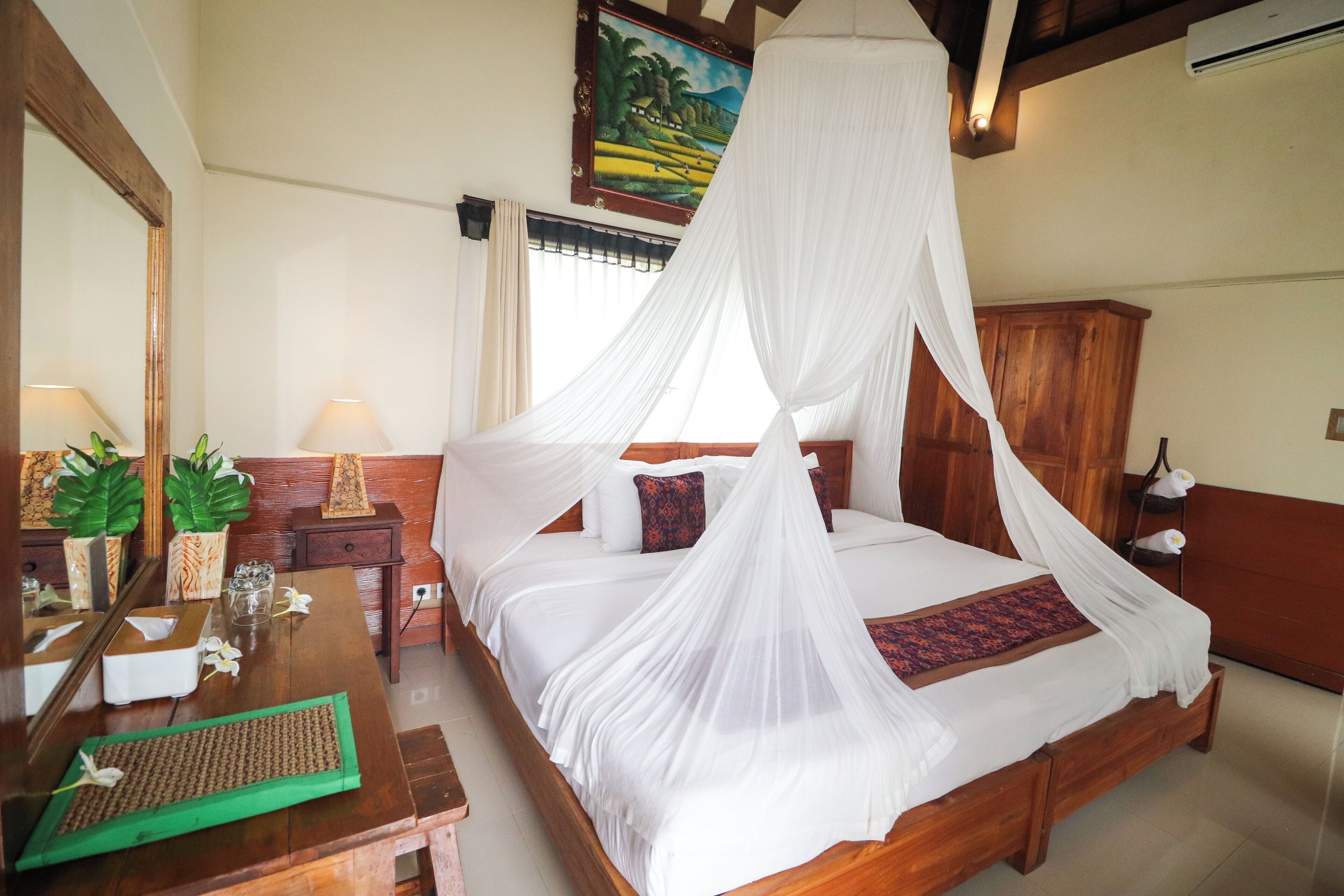 A bedroom with a four-poster bed, a wooden nightstand, a bedside table, and a mirror.
