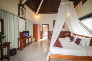 A bedroom with a canopy bed, wooden furniture, and a television. - Villa JJ and Spa Ubud (Ubud)