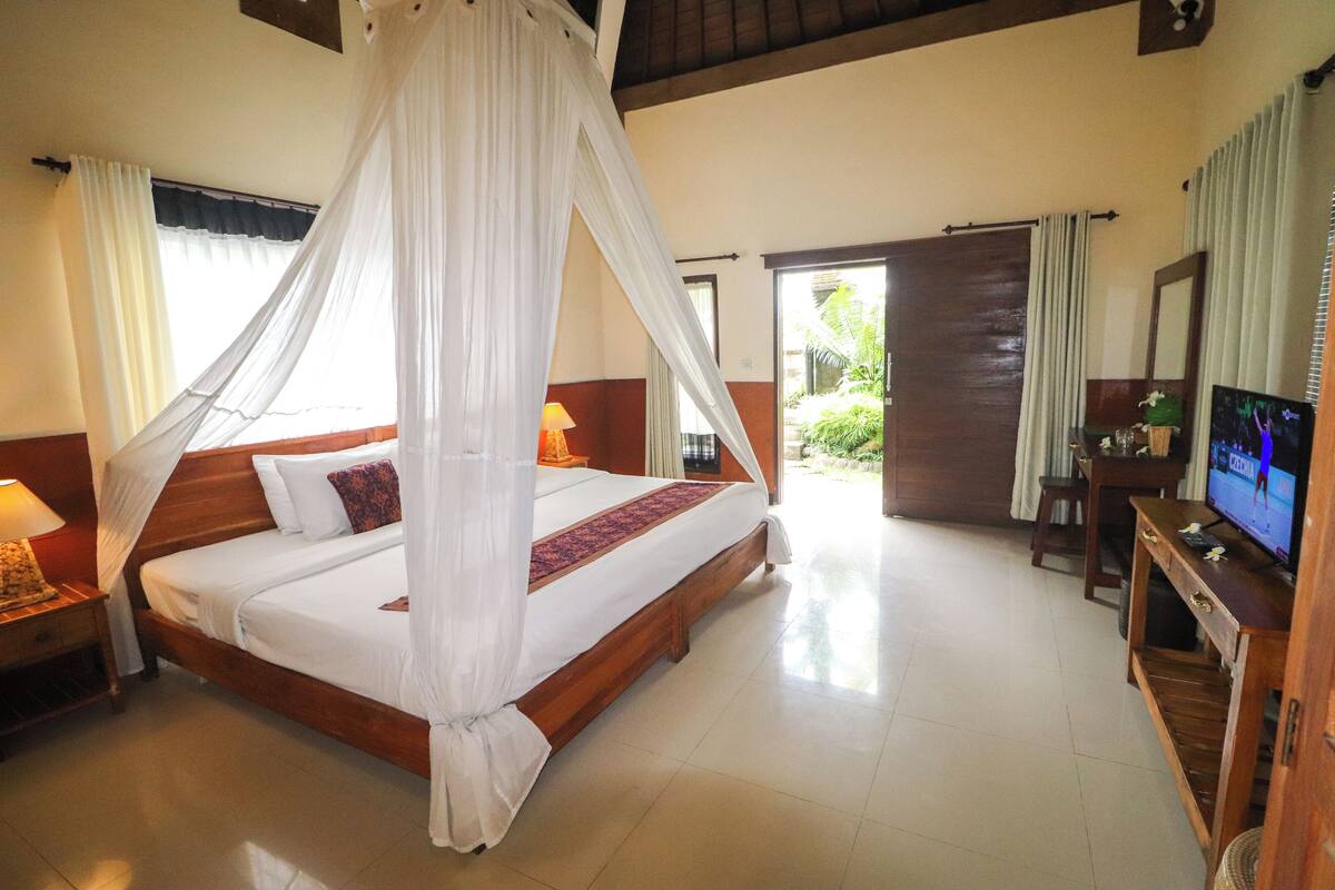 A bedroom with a four-poster bed, a television, and a wooden nightstand.