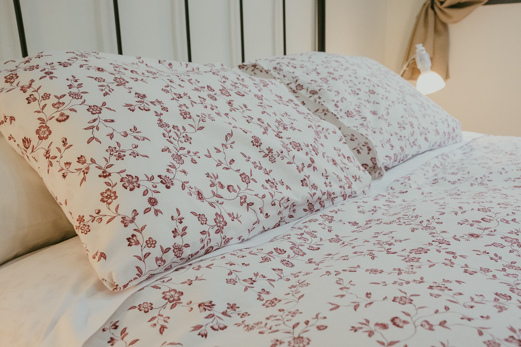 Ein Bett mit blumigem Bettbezug und einer Nachttischlampe.