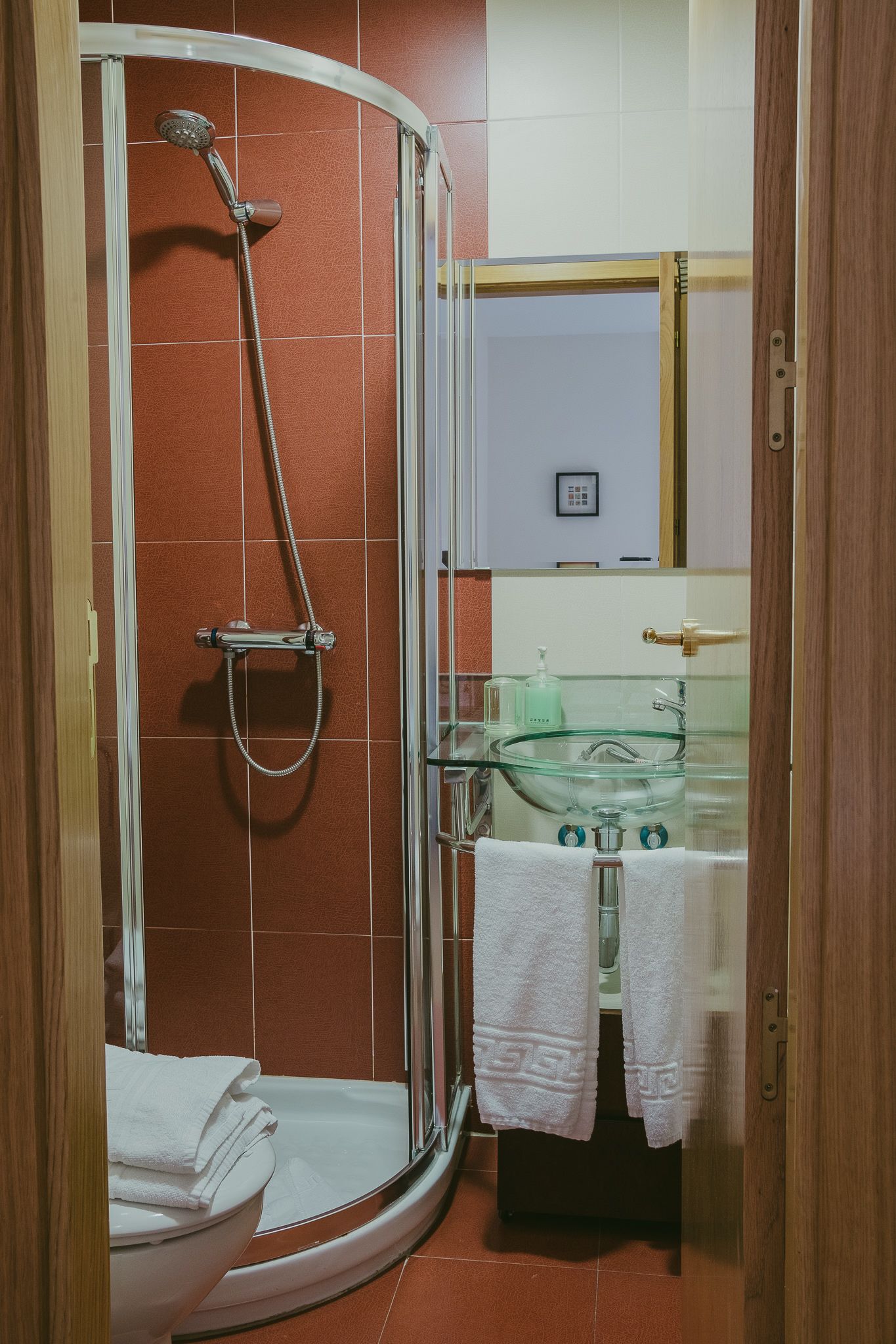 Un baño con cabina de ducha de vidrio, lavamanos de vidrio y un inodoro.